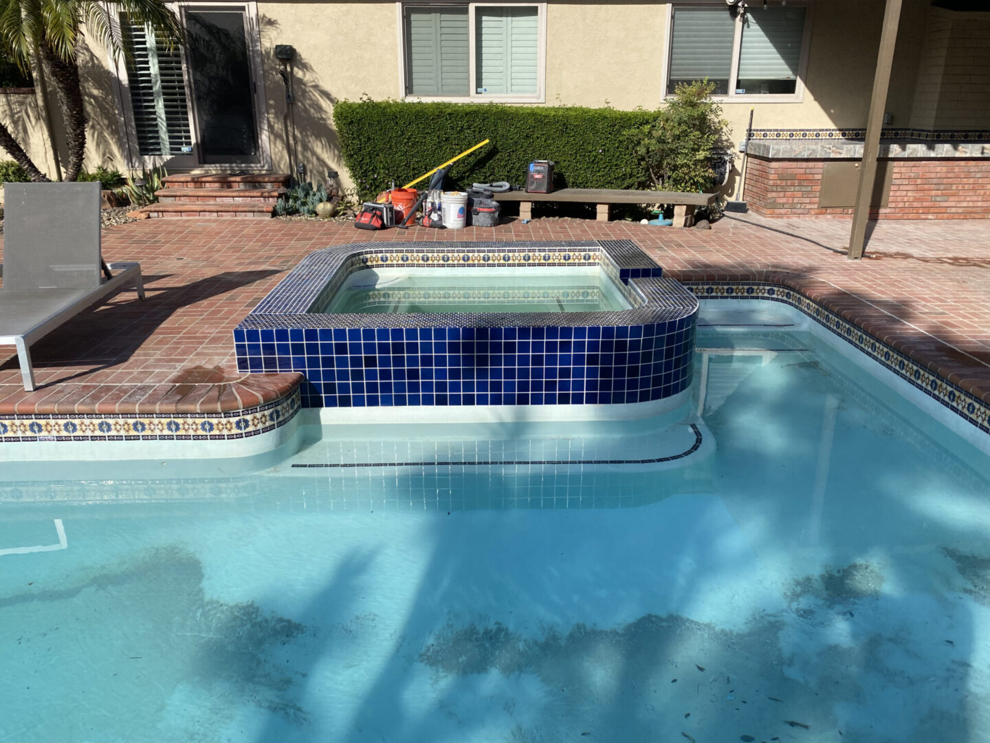 A pool with a blue tile surround and a bench in the background.